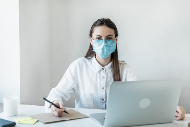 Front view close up of a female in glasses healthcare professional wearing a surgical masks in a hospital. Healthcare workers in the Coronavirus Covid19 pandemic