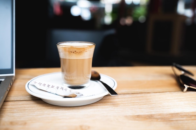 Foto vista frontale tazza di vetro del primo piano con caffè espresso e schiuma di latte