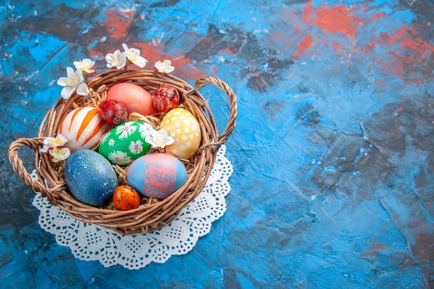 front view colored easter eggs inside basket on blue surface