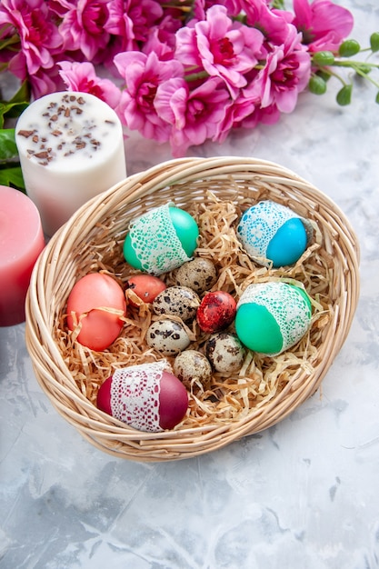 Vista frontale uova di pasqua colorate all'interno del cesto superficie bianca