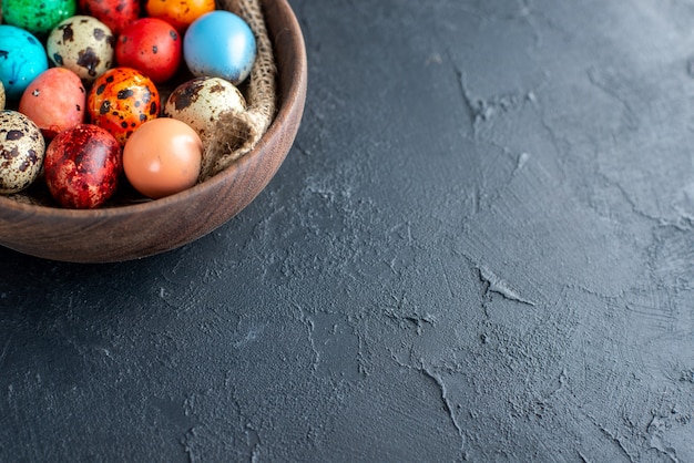 front view colored easter eggs inside brown plate dark surface