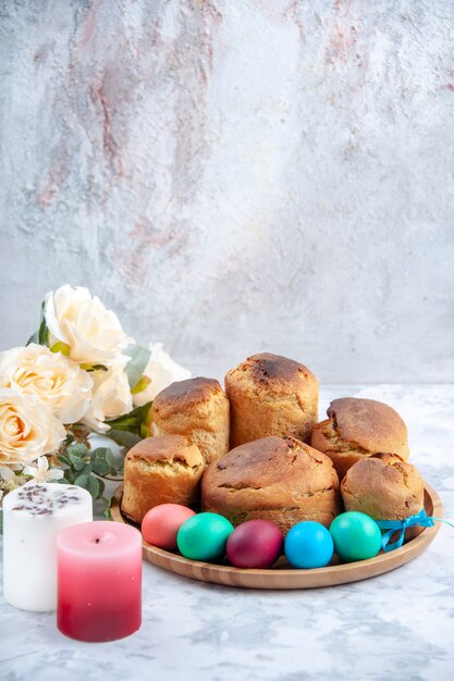 Vista frontale uova di pasqua colorate con pane e torte per le vacanze all'interno del vassoio su sfondo bianco torta dolce ornato colorato primavera