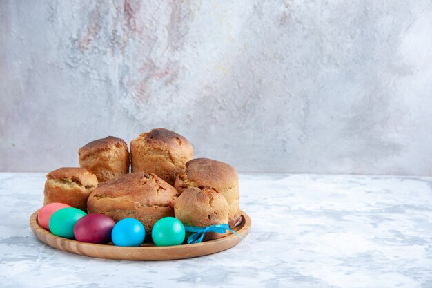 front view colored easter eggs with holiday bread and cakes inside tray on white background spring colourful ornate pie concept sweets