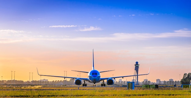 Вид спереди коммерческого самолета на взлетно-посадочной полосе на закате