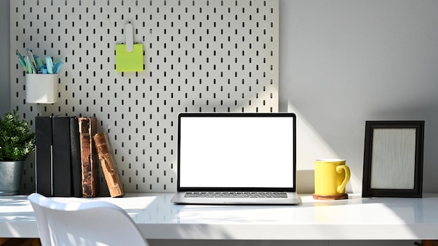 Front view computer laptop stationery books and picture frame\
on white table