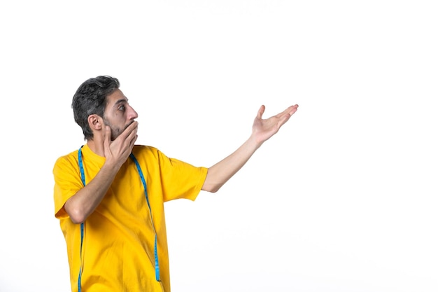 Front view of confused young guy in yellow shirt and holding meter on white surface