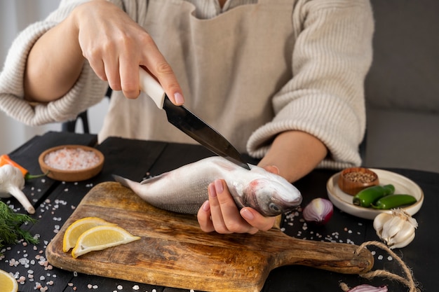 Front view cook cleaning fish in kitchen