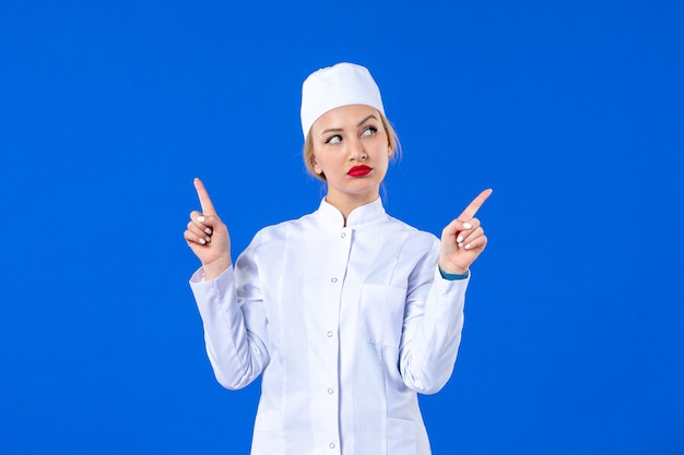 front view of coquette young nurse in white medical suit on blue background pandemic illness hospital virus covid- health disease drug