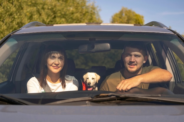 Photo front view couple and dog in the car