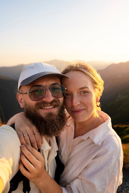 Foto coppie di vista frontale che prendono selfie sulla montagna