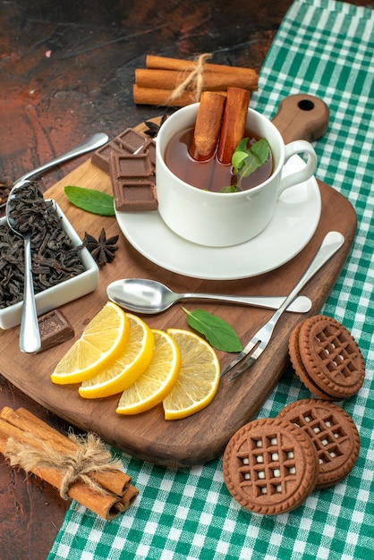вид спереди чашка чая с печеньем и лимоном на темно-коричневом фоне чайный цветок фото цветное печенье аромат кофе