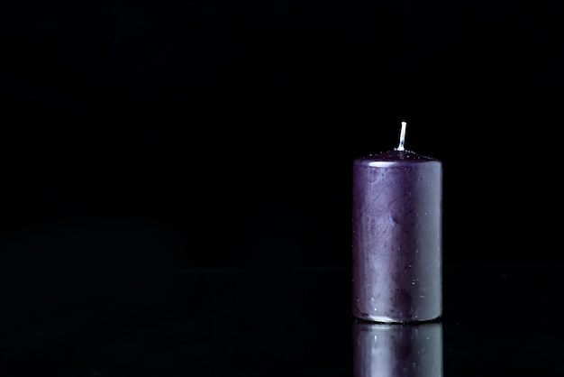 Front view of dark candle on the black surface