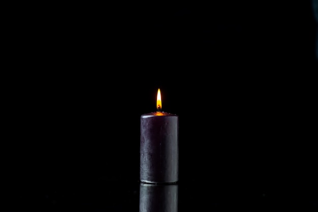 Front view of dark candle lighting on dark surface