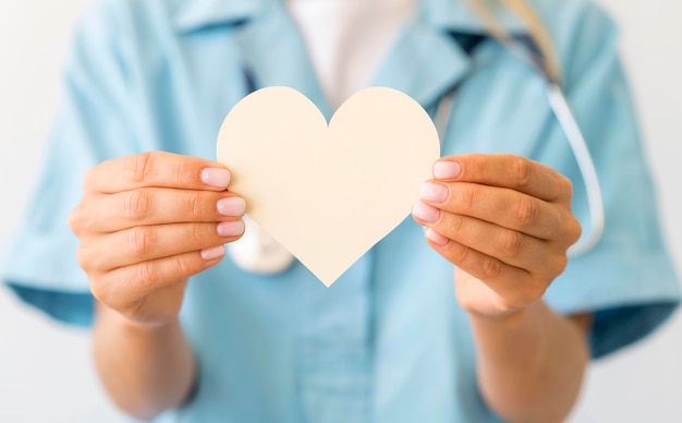 Front view of defocused female doctor holding paper heart