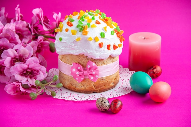 front view delicious cream cake with colored eggs and candle on pink background sugar cake pie sweet dessert colourful ornate novruz spring holidays