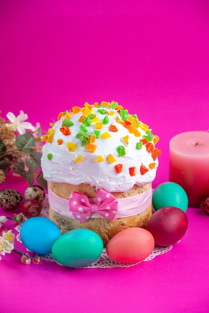 front view delicious cream cake with colored eggs and candle on pink background sugar cake pies sweet dessert colourful ornate novruz spring holiday