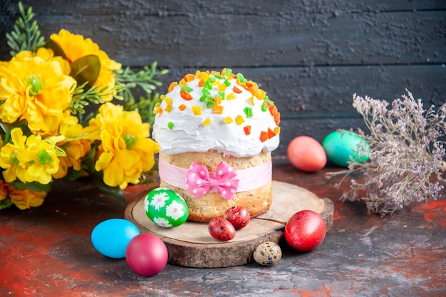 front view delicious cream cake with dried fruits for easter along with colored eggs on dark background colour ethnic easter ornate holiday