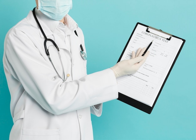 Front view of doctor pointing at coronavirus test on his notepad