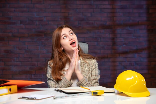 front view dreaming female engineer sitting behind her working place in construction site job agenda contractor business success corporate property builder plan