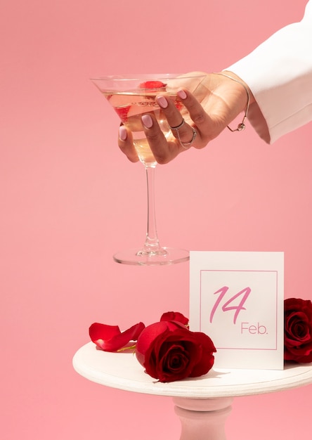Вид спереди напитка в женской руке на день святого валентина и лепестков красной розы