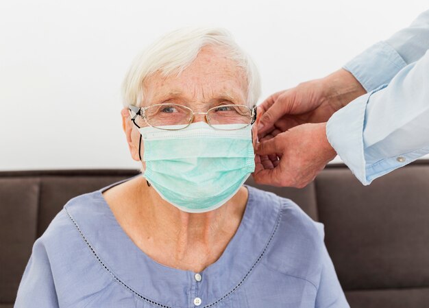 Photo front view of elder woman trying on medical mask