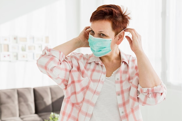 Photo front view of elder woman trying on medical mask