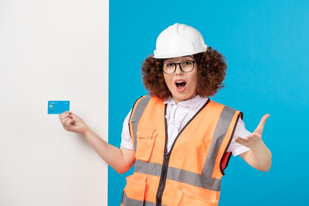 Vista frontale della lavoratrice eccitata in uniforme sulla parete blu