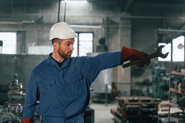 Foto vista anteriore lavoratore di fabbrica in uniforme blu è all'interno