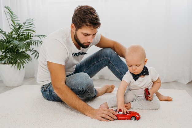 Photo front view of father playing with baby at home