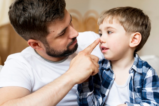 Photo front view father touching his son nose