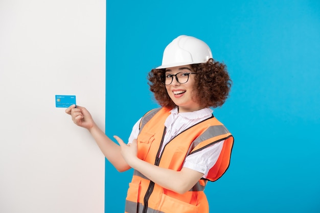 Vista frontale del costruttore femminile in uniforme sulla parete blu