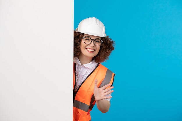 Front view female builder in uniform on blue 