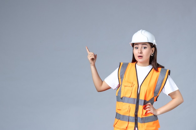 Front view of female builder in uniform on gray wall