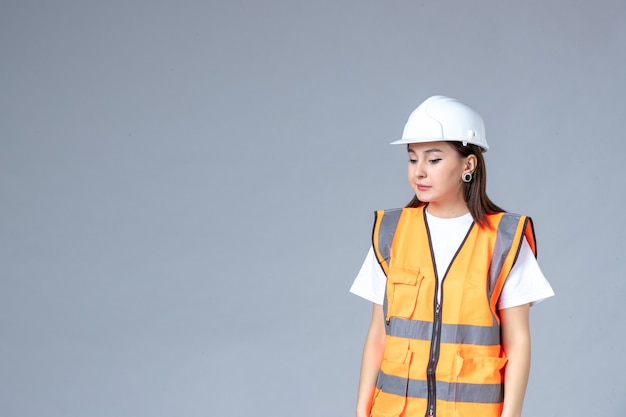 Front view of female builder in uniform on gray wall