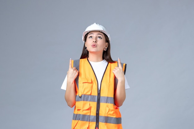 Front view of female builder in uniform on gray wall