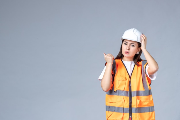 Front view of female builder in uniform on white wall