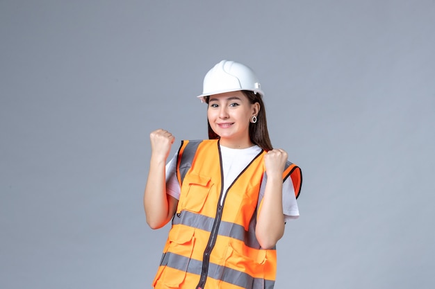Vista frontale del costruttore femminile in uniforme sul muro bianco