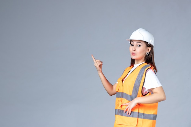 Front view of female builder in uniform on white wall