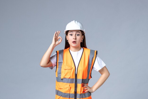 Vista frontale del costruttore femminile in uniforme sul muro bianco