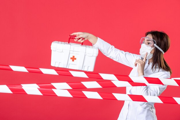 front view female doctor holding first aid kit on red background health line covid- virus medical crime danger sealed