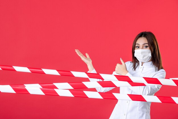 Foto vista frontale dottoressa in uniforme medica e maschera sullo sfondo rosso salute sigillata covid linea ospedaliera criminalità virus pandemico