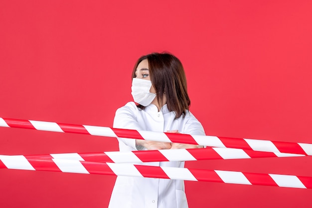 front view female doctor in medical uniform and mask on red background sealed pandemic crime line covid- health hospital