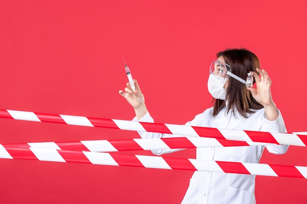 Foto vista frontale dottoressa che prepara l'iniezione su sfondo rosso linea sanitaria crimine sigillato covid- virus ospedaliero medico