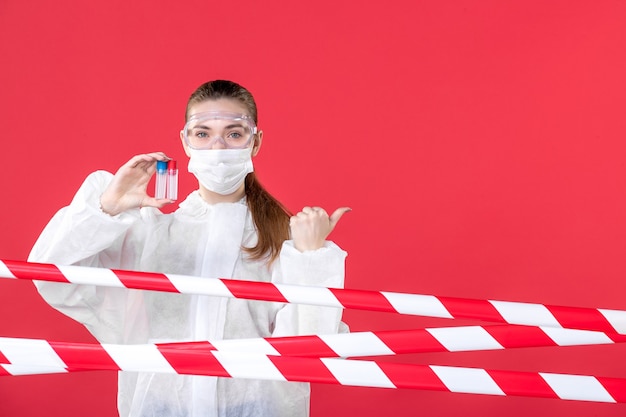 front view female doctor in protective suit holding flasks on a red background hospital covid- health cure tissue nurse emotion virus mask