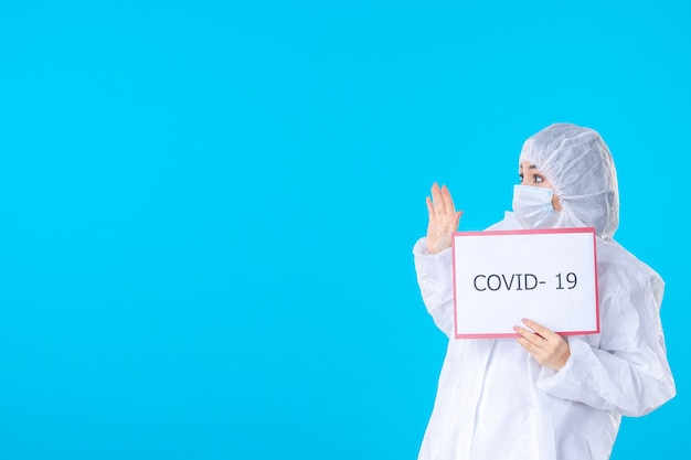 front view female doctor in protective suit and mask on the blue background color covid- medical science health virus isolation pandemic