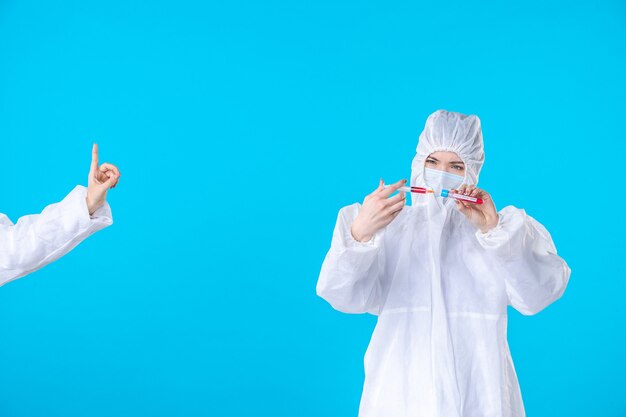 파란색 배경 의료 병원 covid 전염병 건강 과학에 주사를 들고 보호 복과 마스크에 전면보기 여성 의사