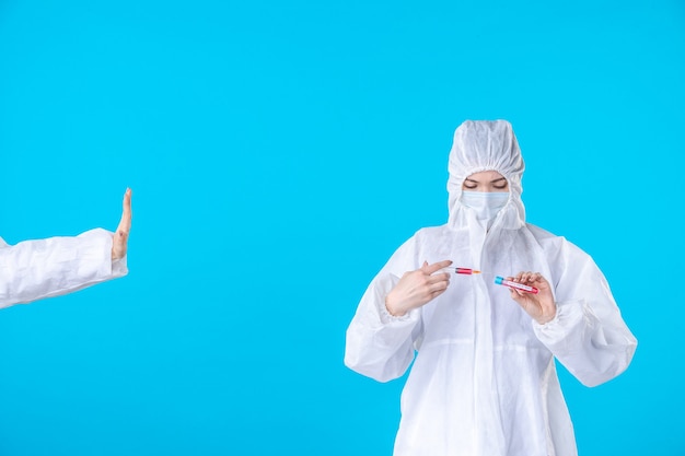 front view female doctor in protective suit and mask holding injection on the blue background medical hospital covid- pandemic virus health science