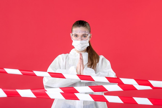 Front view female doctor in protective suit and mask on red\
background tissue nurse covid- health mask hospital cure virus\
emotion