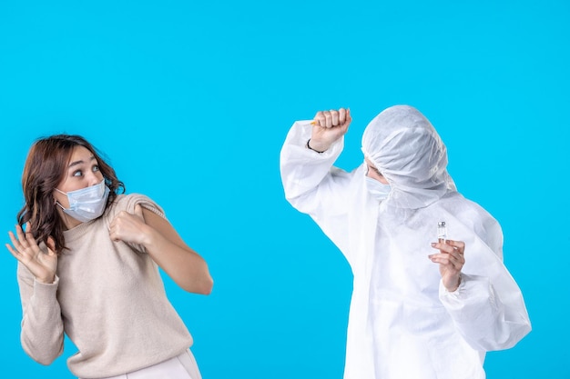 front view female doctor in protective suit preparing to inject patient on the blue background virus disease pandemic health isolation medical covid science