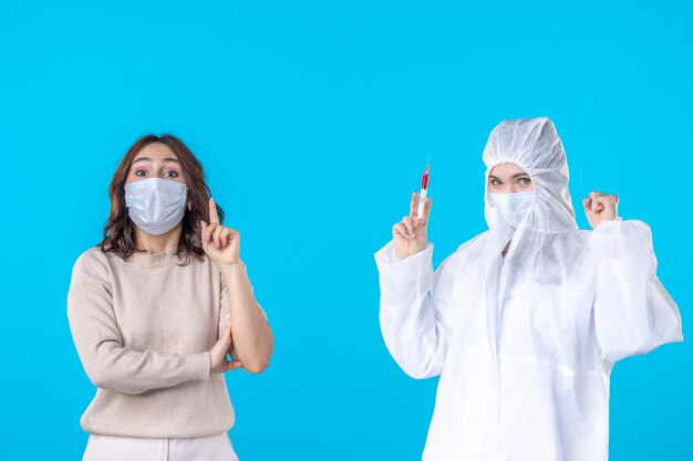 front view female doctor in protective suit with ill patient on the blue background medical virus covid pandemic disease science health isolation